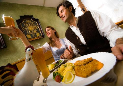 a man and woman sitting at a table with a plate of food at Posthotel Kolberbräu in Bad Tölz