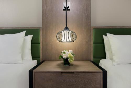 a room with two beds and a table with flowers at Oxford Suites Paso Robles in Paso Robles