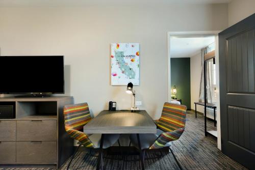 a living room with a table and chairs and a tv at Oxford Suites Paso Robles in Paso Robles