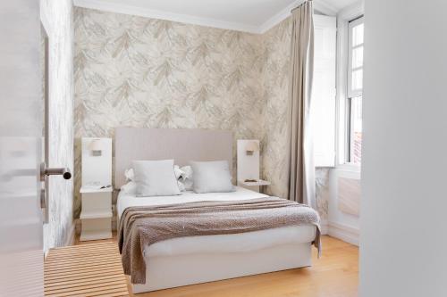 リスボンにあるChiado Apartments by Courtesy Morningの白いベッドと壁が備わるベッドルーム1室が備わります。