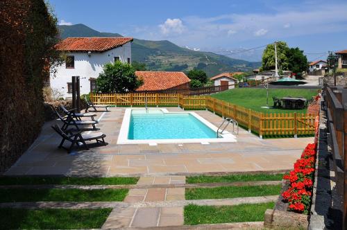 einen Pool in einem Garten mit Stühlen und Blumen in der Unterkunft Casa Rural Los Llares in Lerones