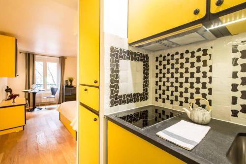 une cuisine avec des armoires jaunes et un comptoir jaune dans l'établissement CHARMING LE MARAIS RETRO, à Paris