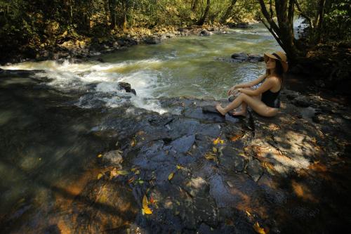 a woman sitting on a log in the middle of a river at Vivaz Cataratas Hotel Resort in Foz do Iguaçu