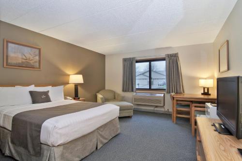 Habitación de hotel con cama y TV en Boarders Inn & Suites by Cobblestone Hotels - Faribault, en Faribault
