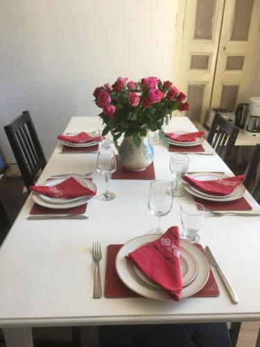 a white table with red napkins and a vase of pink roses at Ancien Relais de Poste The Old Post Office in Saint-Martial-dʼAlbarède