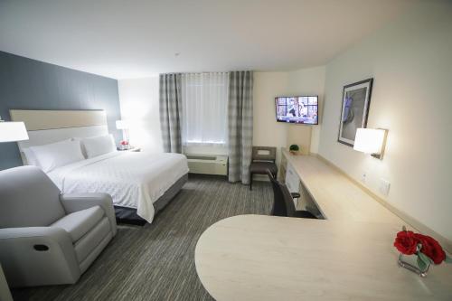 a hotel room with a bed and a chair and a table at Candlewood Suites Miami Intl Airport - 36th St by IHG in Miami