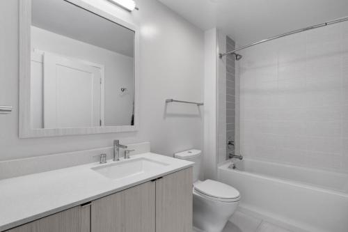 Global Luxury Suites Crystal City في أرلينغتون: حمام مع حوض ومرحاض ومرآة