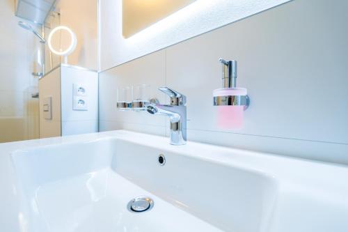 een witte badkamer met een wastafel en een kraan bij Ferienwohnung am Kleinbahnhof in Binz