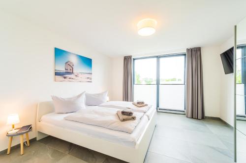 een slaapkamer met een wit bed en een groot raam bij Ferienwohnung am Kleinbahnhof in Binz