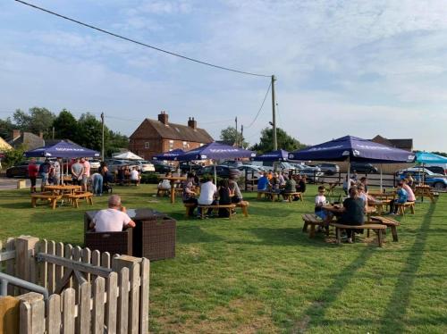 eine Gruppe von Personen, die an Tischen unter blauen Sonnenschirmen sitzen in der Unterkunft The Queens At Horton in Telford