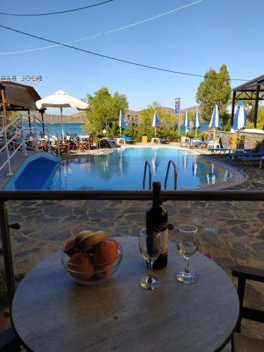 a table with a bowl of fruit and a bottle of wine at Lena Apartments in Elounda