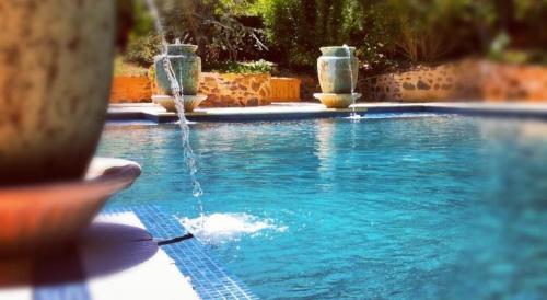 a person is swimming in a pool with a surfboard at Jacobs Creek Retreat - Barossa Valley in Tanunda