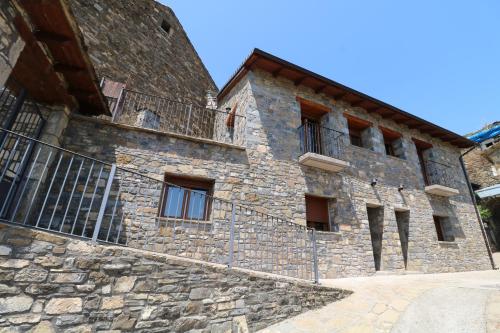 un antiguo edificio de piedra con una valla lateral en Casas Rurales Bestue-Ordesa, en Bestué