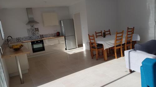 uma cozinha e sala de jantar com mesa e cadeiras em Maison Neuve Moderne em Fresney-le-Vieux