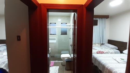 a room with a bedroom with two beds and a mirror at Pousada Monte Carlo in São Joaquim