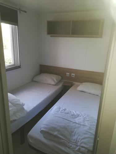deux lits dans une petite pièce avec une fenêtre dans l'établissement MOBIL HOME 3ch 2sdb A LATTES, à Lattes