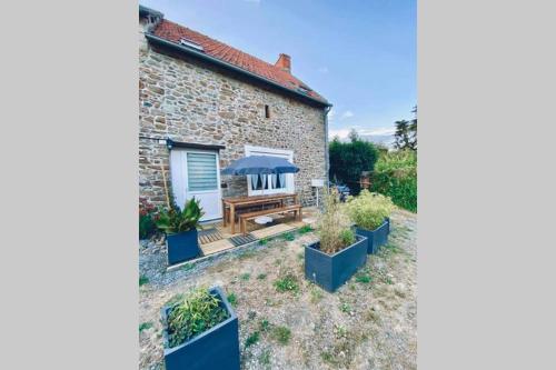 uma casa de pedra com um jardim e um pátio em Le Cosy B em La Gouesnière