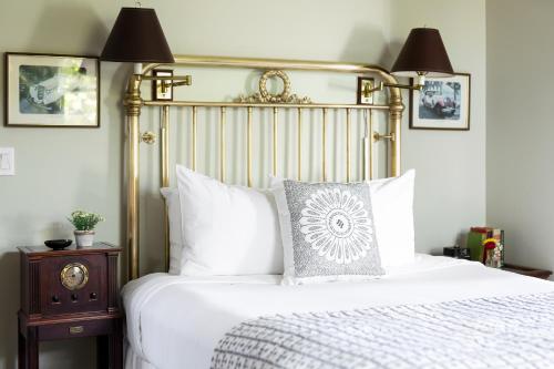 a bedroom with a white bed with a gold headboard at Garden Street Inn Downtown San Luis Obispo, A Kirkwood Collection Hotel in San Luis Obispo