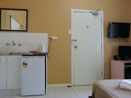 a kitchen with a refrigerator and a door with a television at Central Private Hotel in Sydney