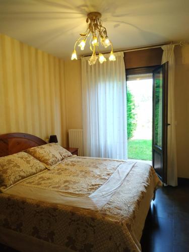 a bedroom with a bed with a window and a chandelier at Apartamento Golf con Jardin Sojuela in Sojuela