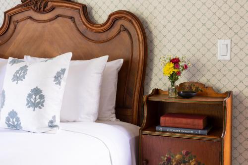 a bedroom with a bed and a vase of flowers on a night stand at Garden Street Inn Downtown San Luis Obispo, A Kirkwood Collection Hotel in San Luis Obispo