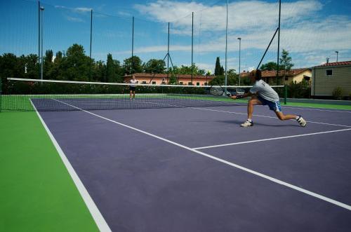 two people playing tennis on a tennis court at San Francesco Camping Village in Desenzano del Garda