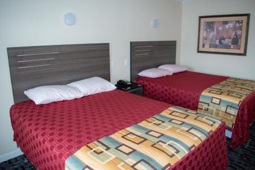 two beds in a hotel room with red sheets at Inn of Lenoir Motor Lodge in Lenoir City