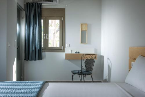 a bedroom with a chair and a bed and a window at royal nest in Matala