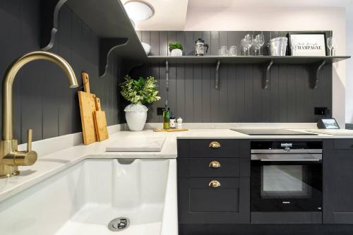 eine Küche mit schwarzen und weißen Arbeitsflächen und einem Waschbecken in der Unterkunft The Cottage - Luxury Romantic Retreat in Idyllic Rural Location in Clipston
