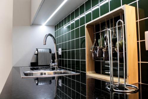 a bathroom with a sink and green tiled walls at Casa Jardim By Alojamento Ideal in Porto