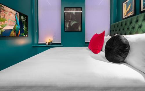 a bedroom with a large white bed with red pillows at Hux Hotel, Kensington in London