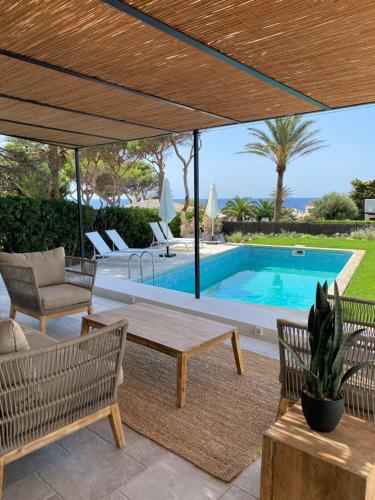patio ze stołem i krzesłami oraz basenem w obiekcie BiniFa - Lovely luxury villa few steps from the sea w mieście Binibeca