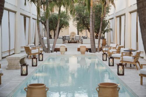a swimming pool in a building with chairs and trees at Cara Hotel in Los Angeles
