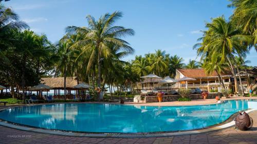 een zwembad in een resort met palmbomen bij Saigon Mui Ne Resort in Mũi Né