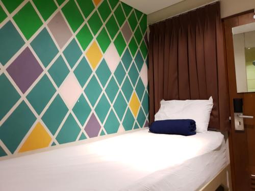 Subwow Hostel في باندونغ: غرفة نوم مع سرير وجدار ملون