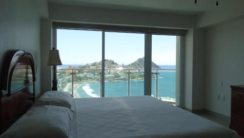 a bedroom with a bed and a view of the ocean at Suite Chiametlan Cerro de la Neveria MZ in Mazatlán