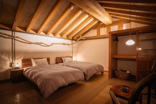a bedroom with two beds in a room with wooden ceilings at Bed and Craft RoKu in Nanto