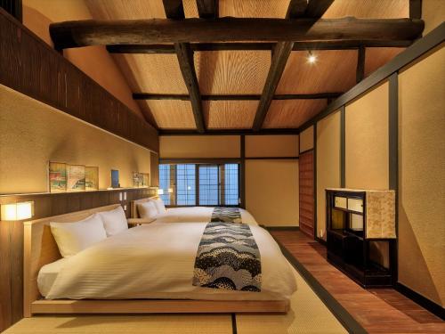 ein Schlafzimmer mit einem großen Bett und einer Holzdecke in der Unterkunft Tsumugi Nishinotoinhanayacho in Kyoto