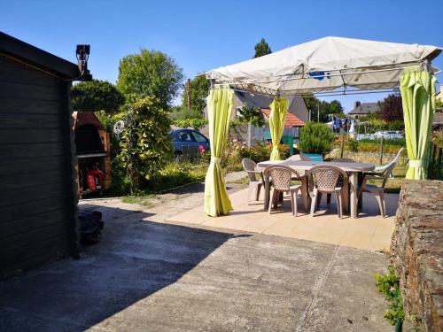 patio con tavolo e sedie sotto un baldacchino di Duplex à 2km de la Baie de Cancale-Mt St Michel a La Fresnais