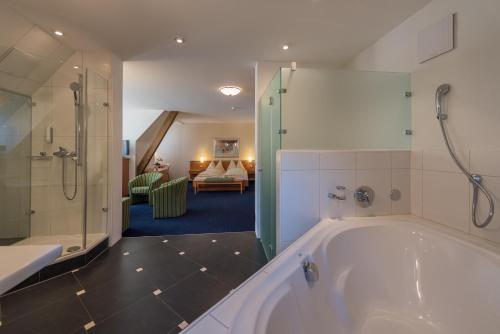a large bathroom with a tub and a bedroom at Parkhotel Gunten – Beach & Spa in Gunten