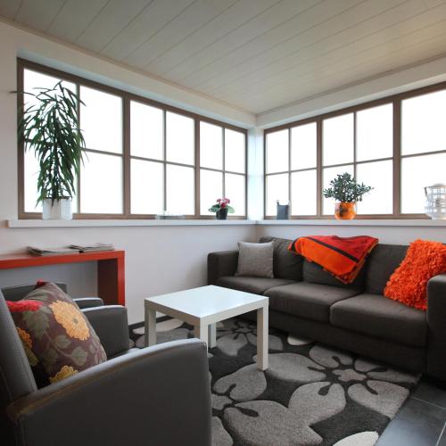 a living room with couches and a table and windows at B&B Back2Front in Boezinge