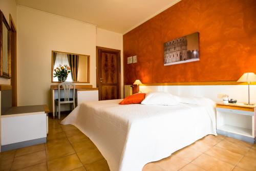 a bedroom with a white bed with an orange wall at Hotel Roma in Pisa