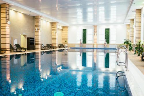 a large swimming pool with chairs in a building at Grumant Resort & Spa in Yasnaya Polyana