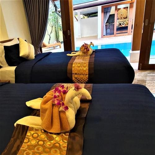 two beds in a hotel room with towels on them at Orange palm pool villa in Chaweng
