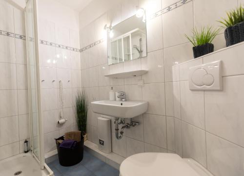 a white bathroom with a toilet and a sink at Ferienwohnung "Sylt Sunrise" in Westerland (Sylt)
