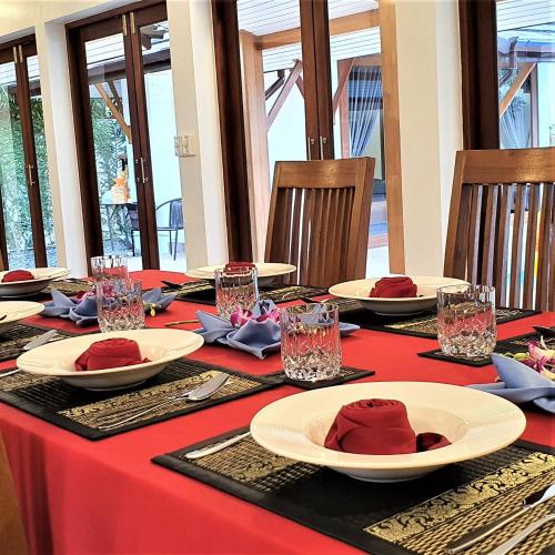 a table with a red table cloth and plates on it at Orange palm pool villa in Koh Samui 