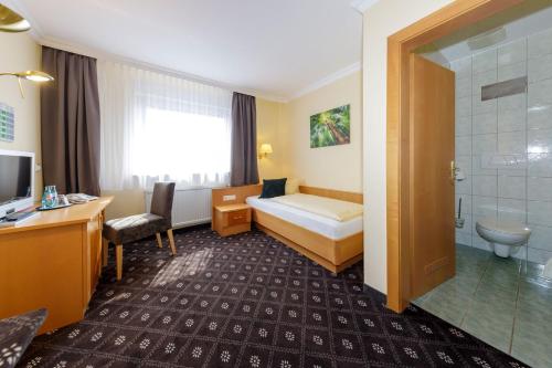 a hotel room with a bed and a bathroom at Hotel Zum Adler in Nidderau