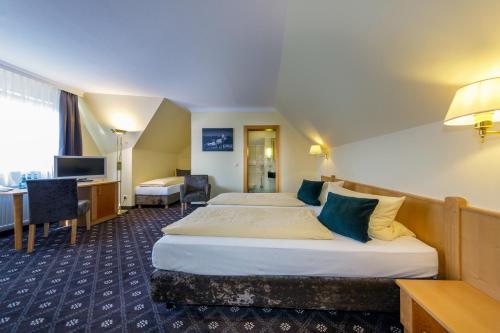 Habitación de hotel con 2 camas y escritorio en Hotel Zum Adler, en Nidderau