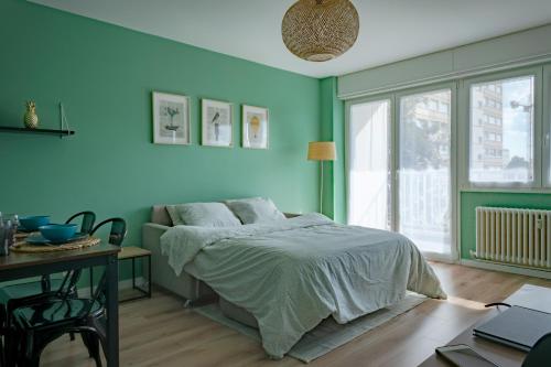 a bedroom with blue walls and a bed and a table at Le Colibri - Stationnement gratuit - Balcon - Jusqu'à 4 personnes in Metz