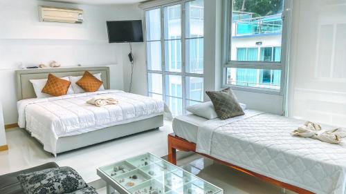 a bedroom with two beds and a couch and a window at Khung Wimarn Beach home by 3Angels in Chanthaburi